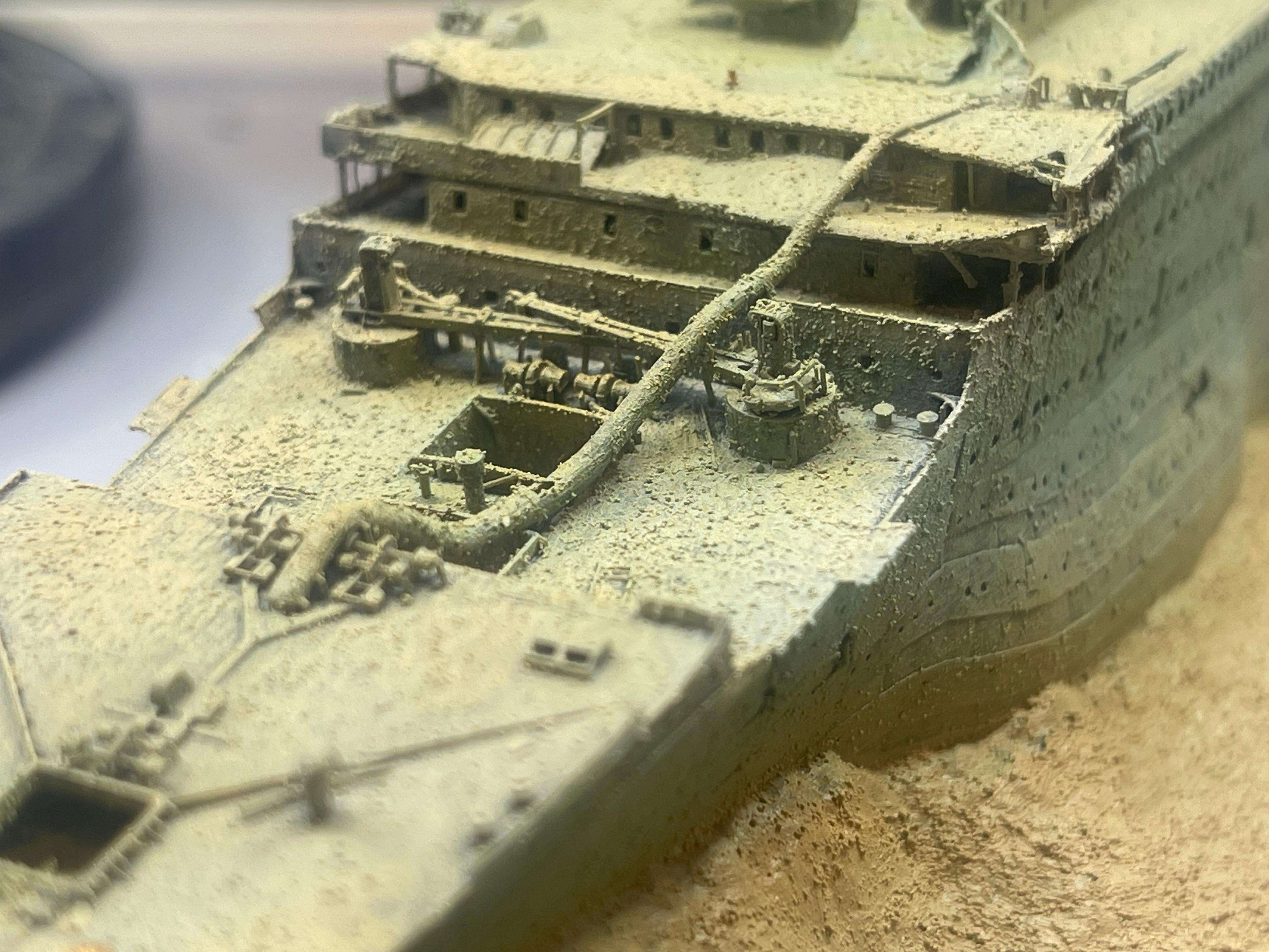 Close-up of a detailed model of the Titanic wreck on a sandy surface