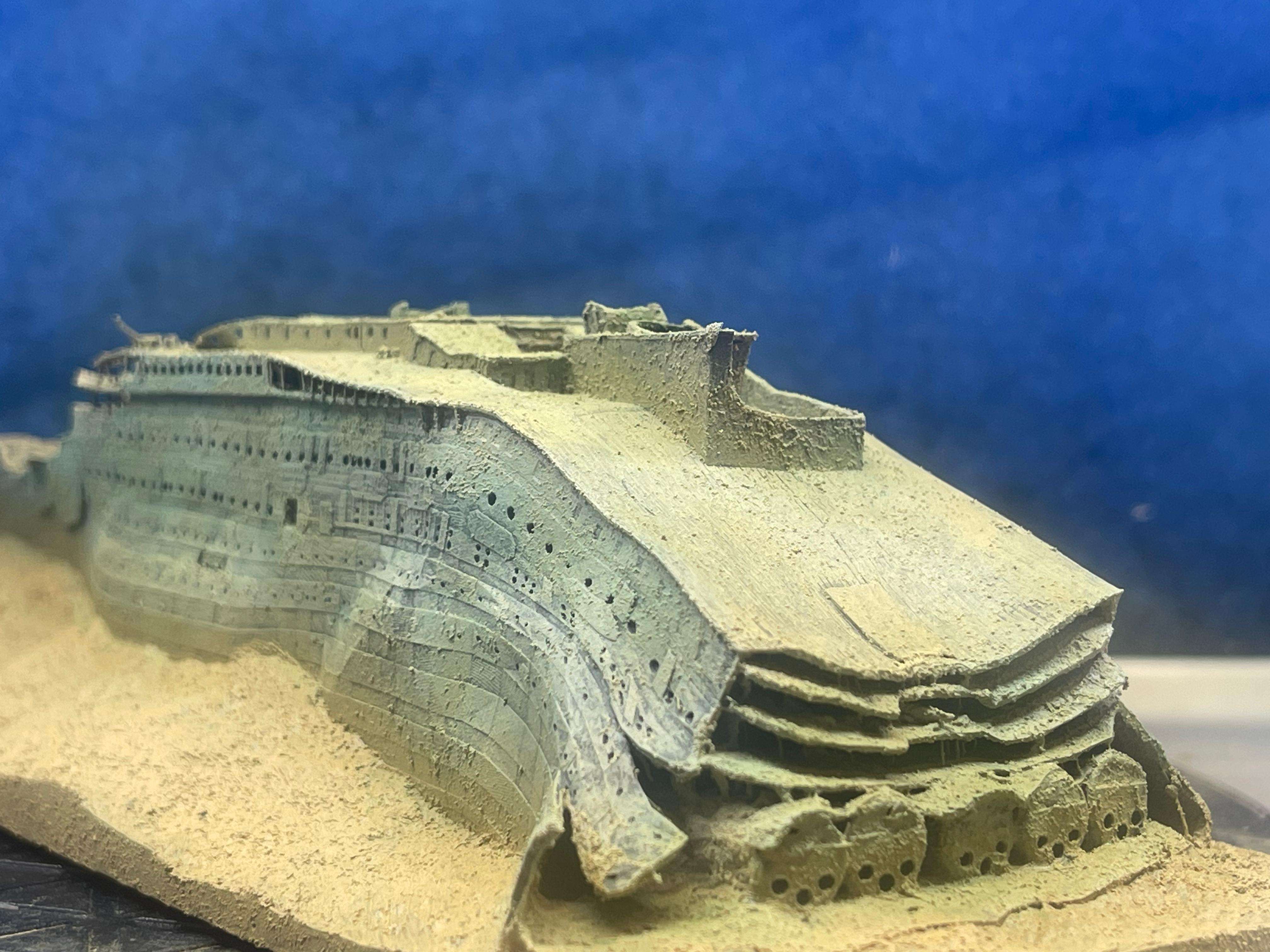 Close-up of a detailed model of the Titanic wreck on a sandy surface